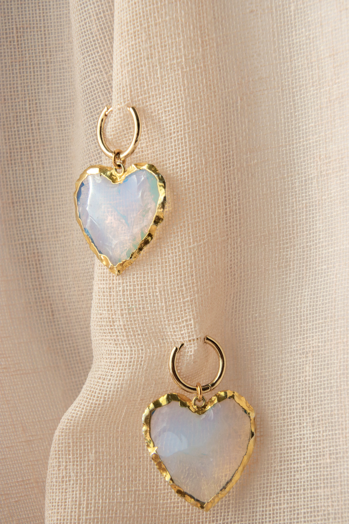 Our Opalite heart shaped earrings on a light pink background