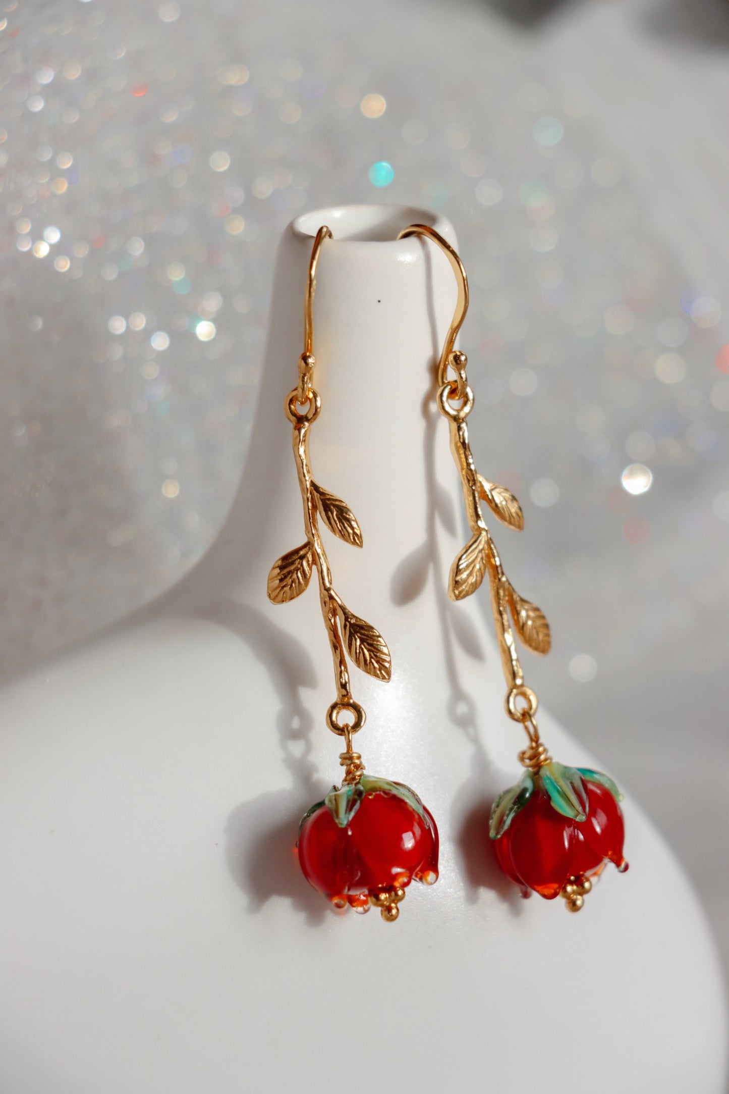 A pair of earrings shaped like roses. They are about 8cm long made of silver and glass red roses.