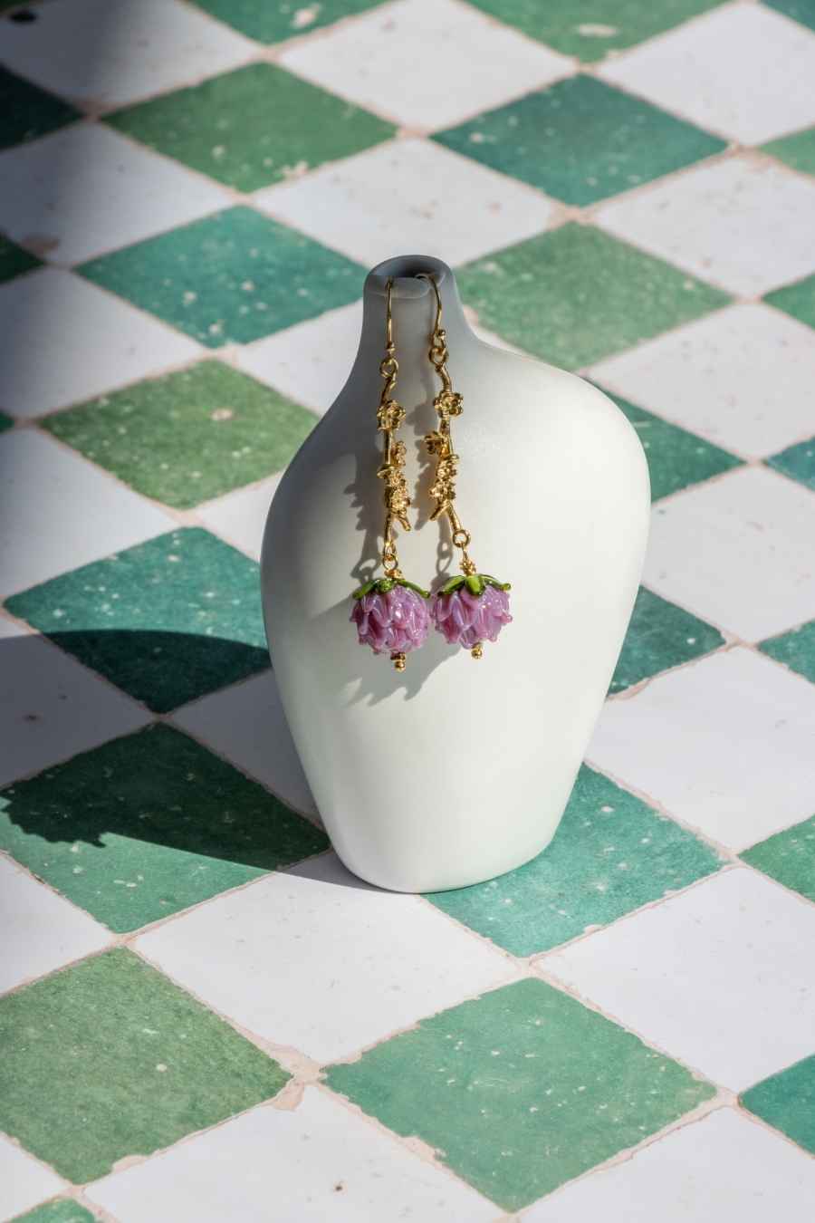 a more distant shot of the earrings hagging on a vase