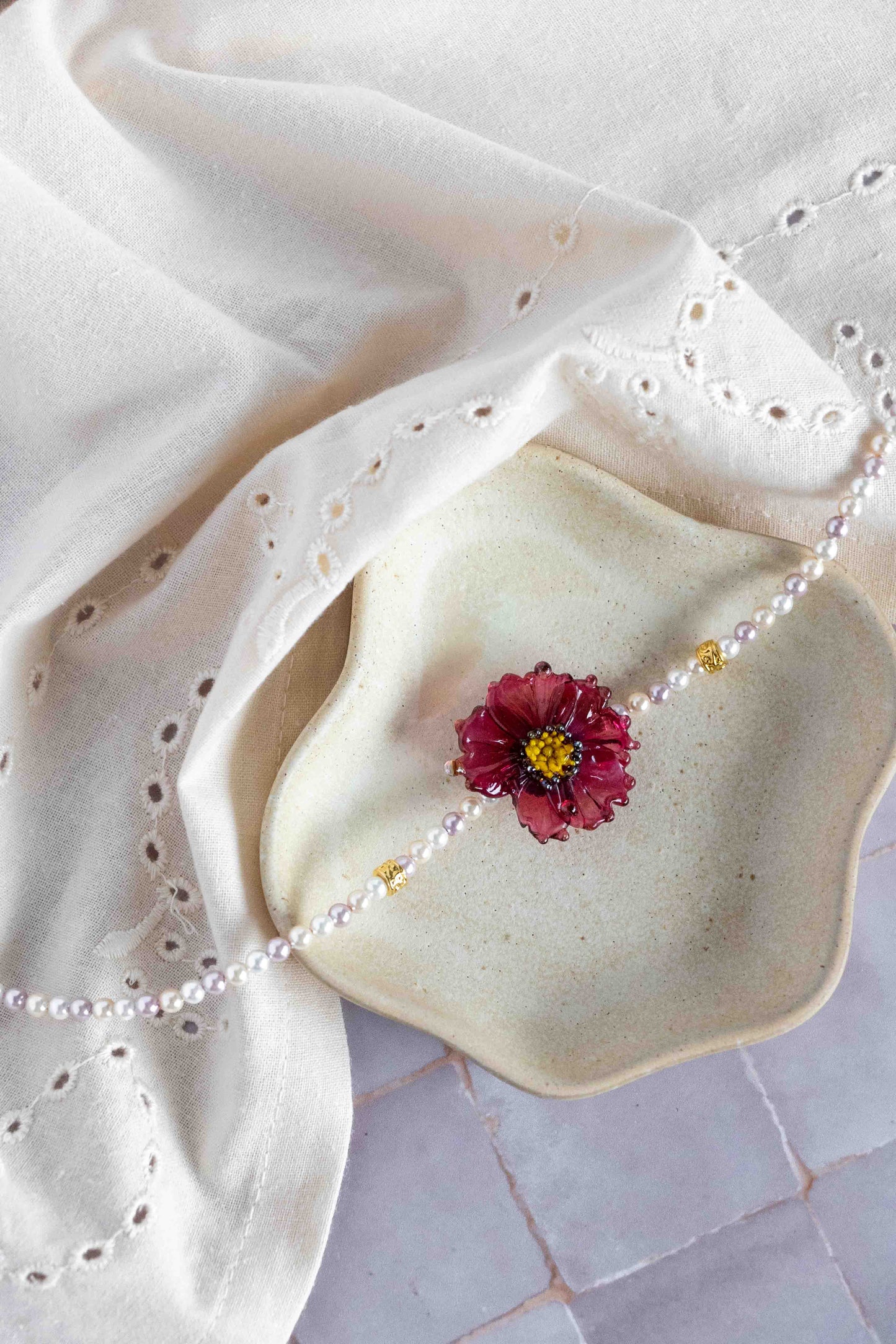 Necklace with a pink flower pendant on a white fabric background