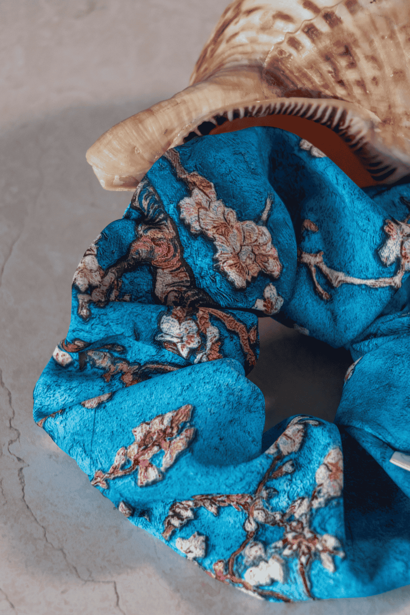 Detail of a blue floral scrunchie on a textured surface