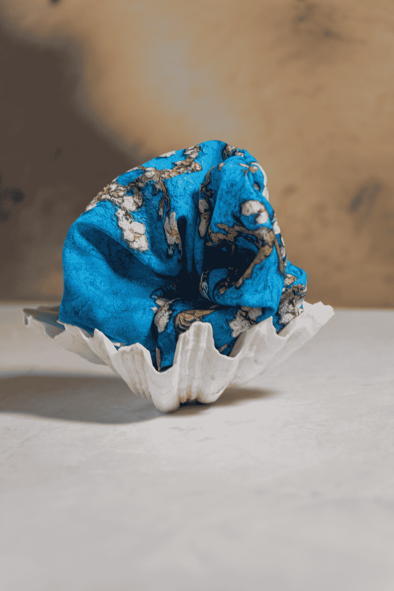 Blue Scrunchie in a sea shell on a neutral background