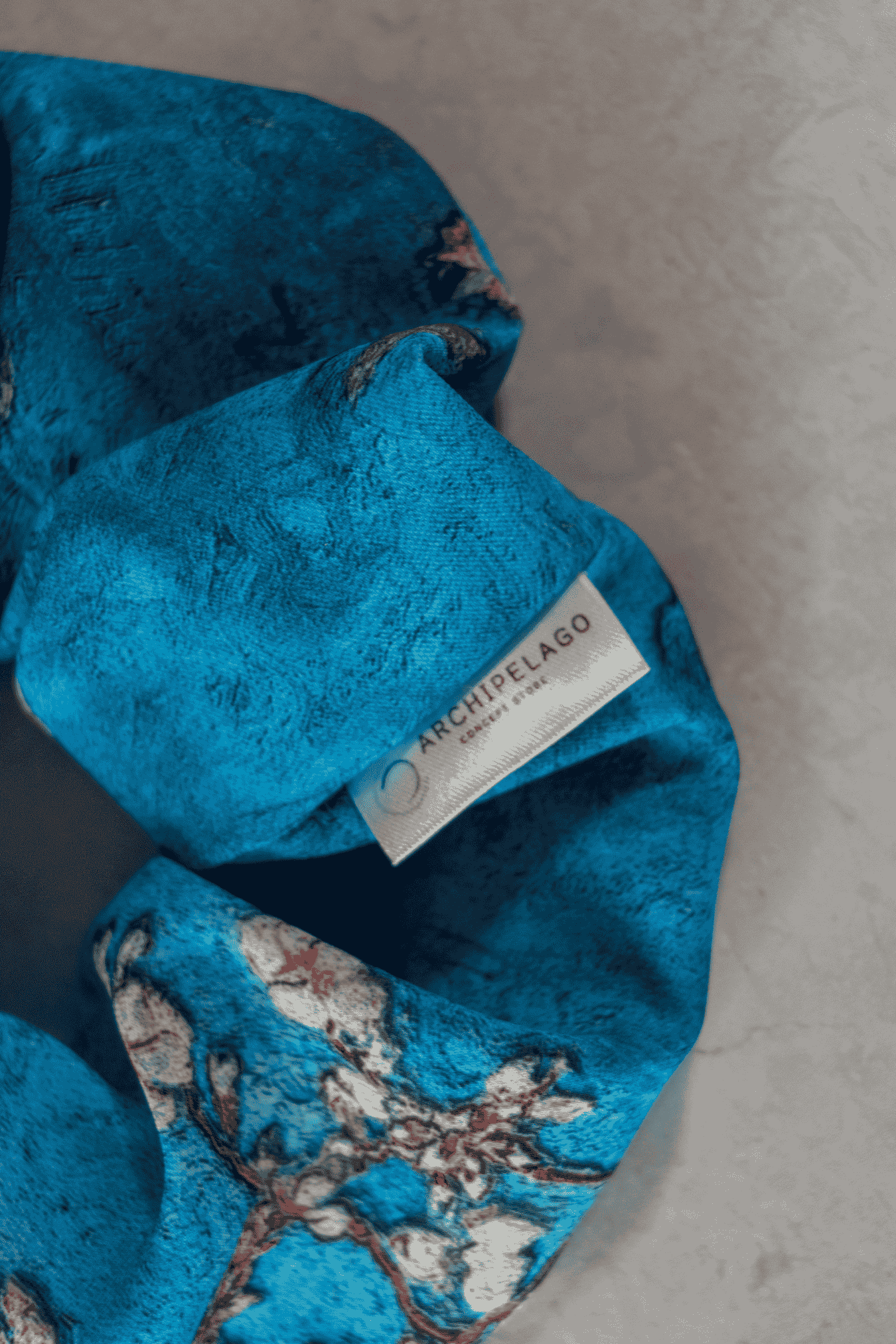 Detail of the blue textured fabric with a brand label on a gray surface