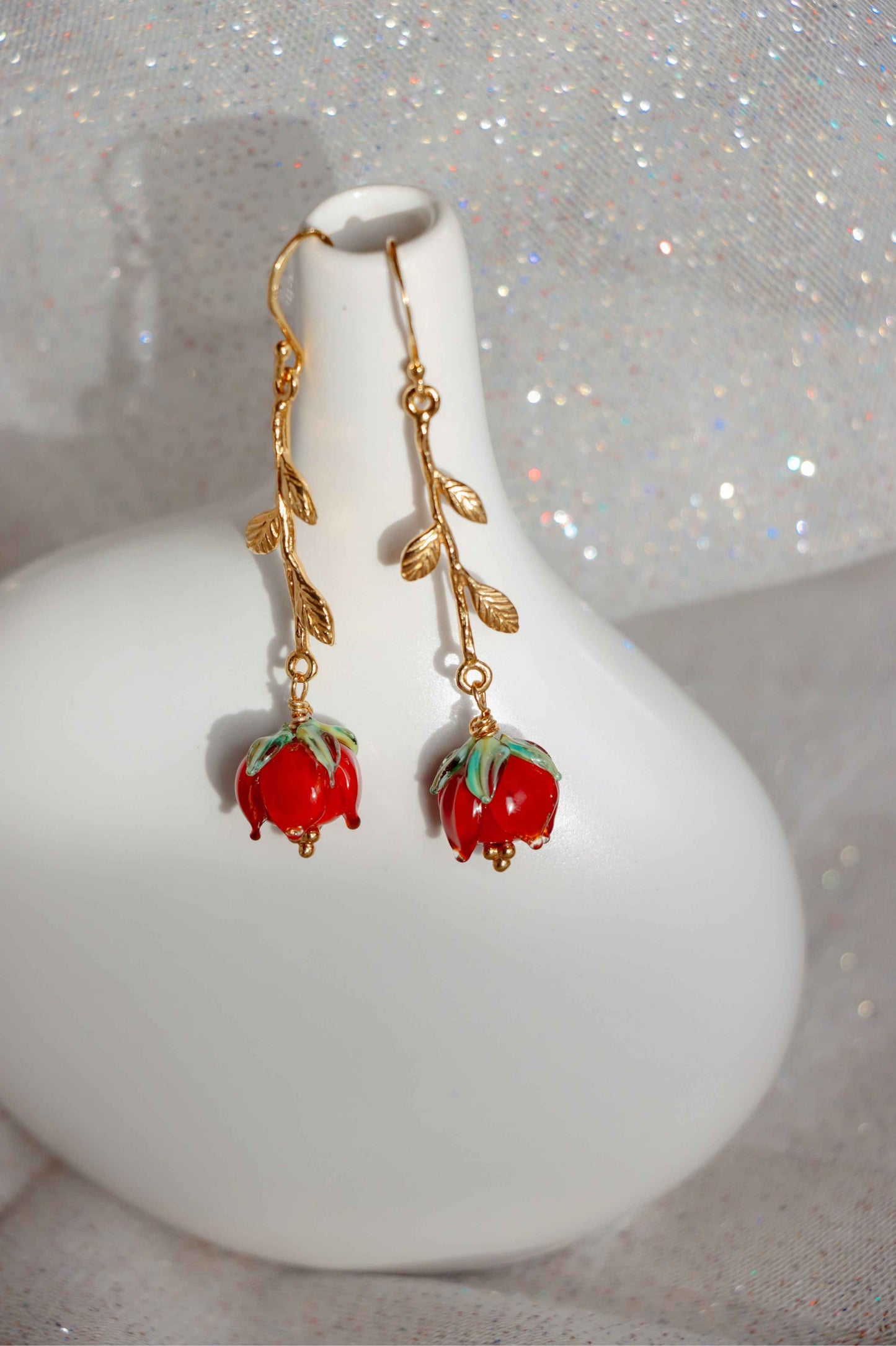 A pair of earrings shaped like roses. They are about 8cm long made of silver and glass red roses.