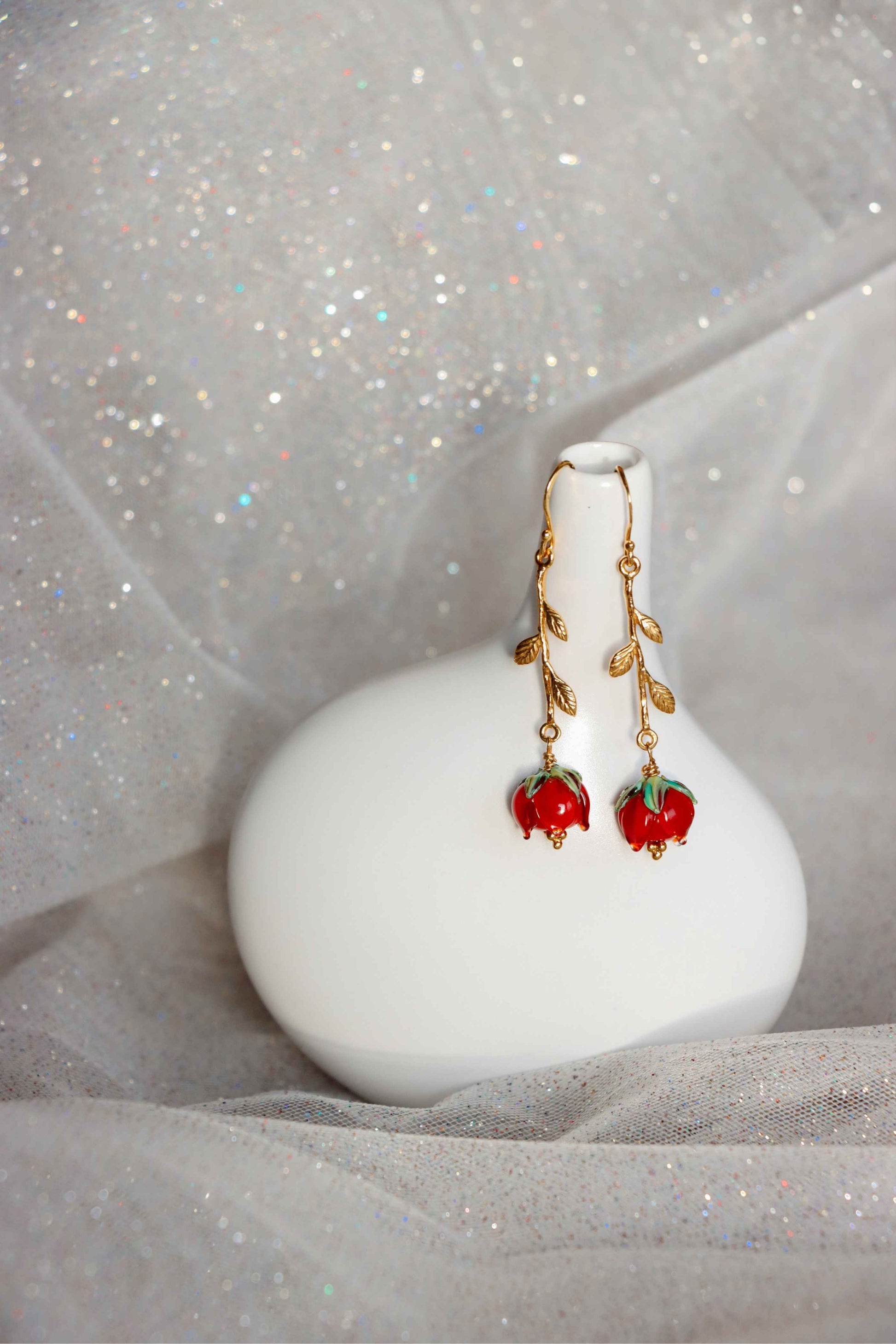 A pair of earrings shaped like roses. They are about 8cm long made of silver and glass red roses.