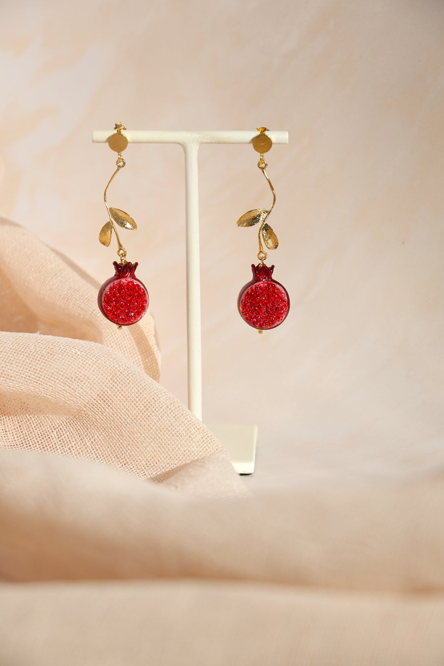 Red earrings with gold accents on a beige background