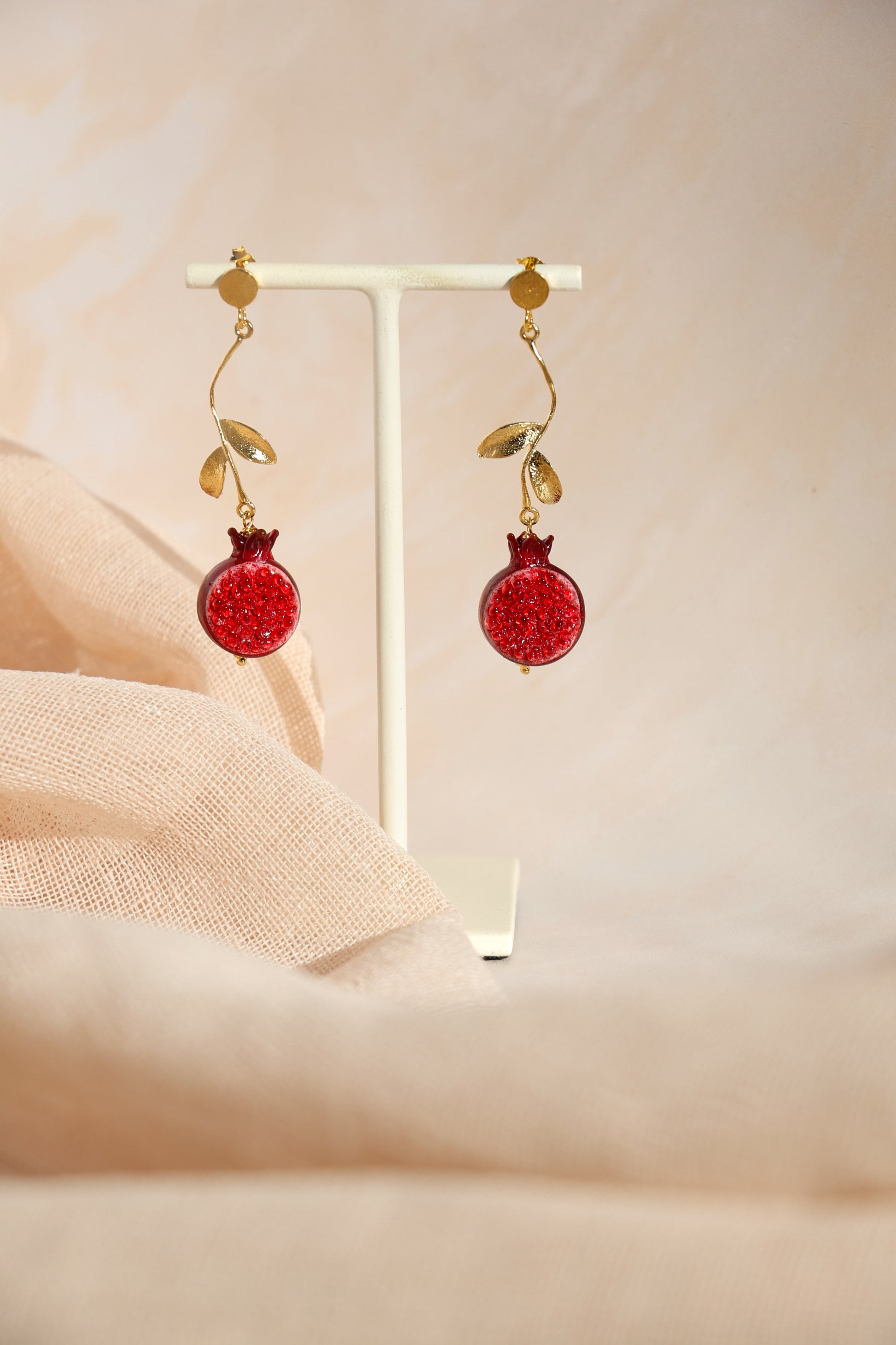 Red earrings with gold accents on a beige background