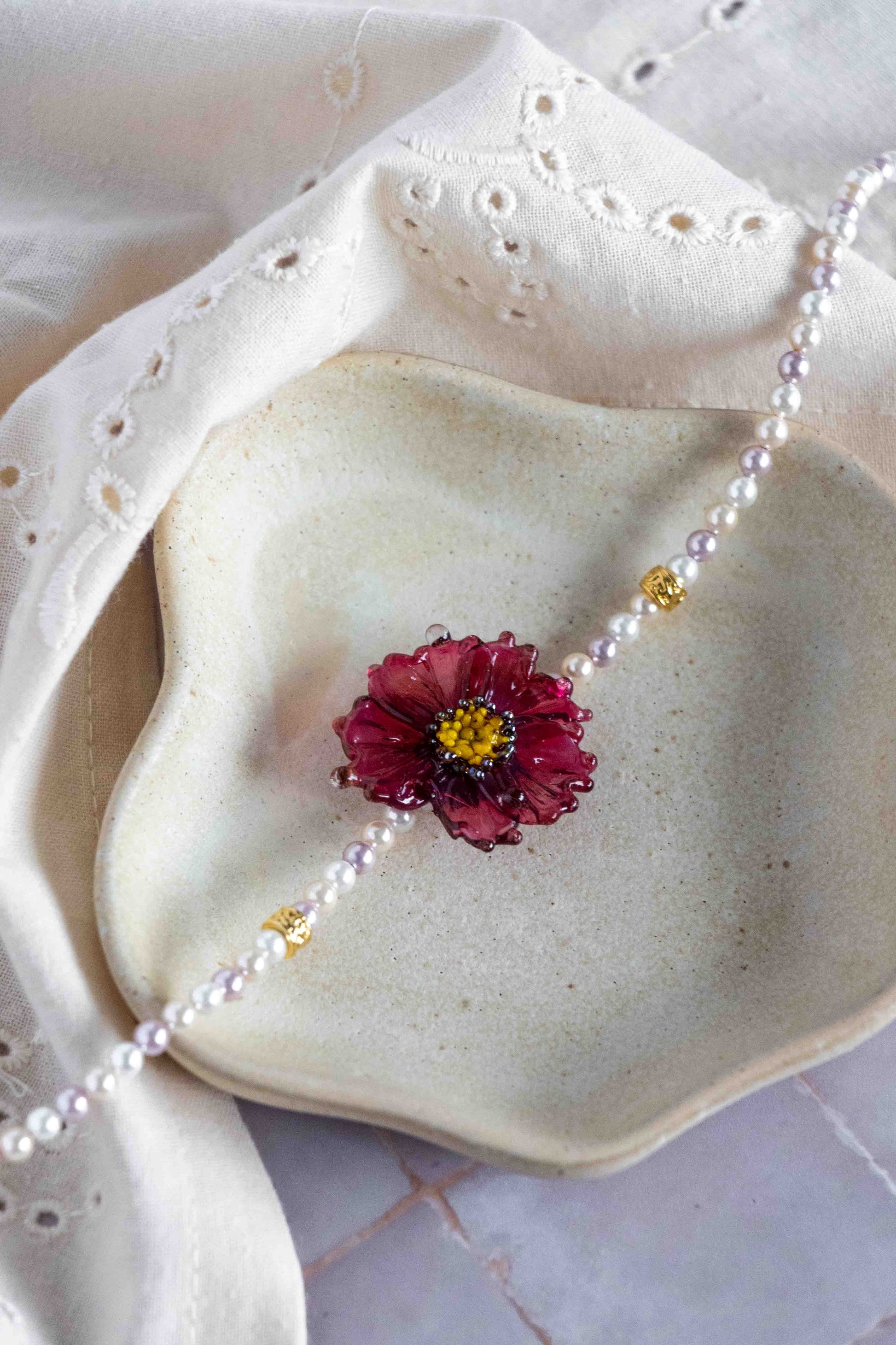 Pearl necklace with a floral glass brooch on a textured surface