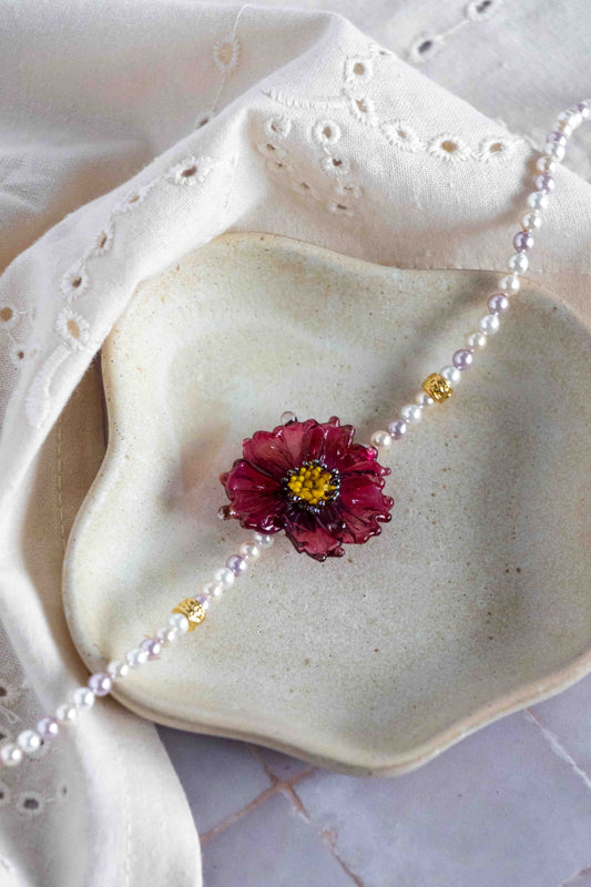 Pearl necklace with a floral glass brooch on a textured surface