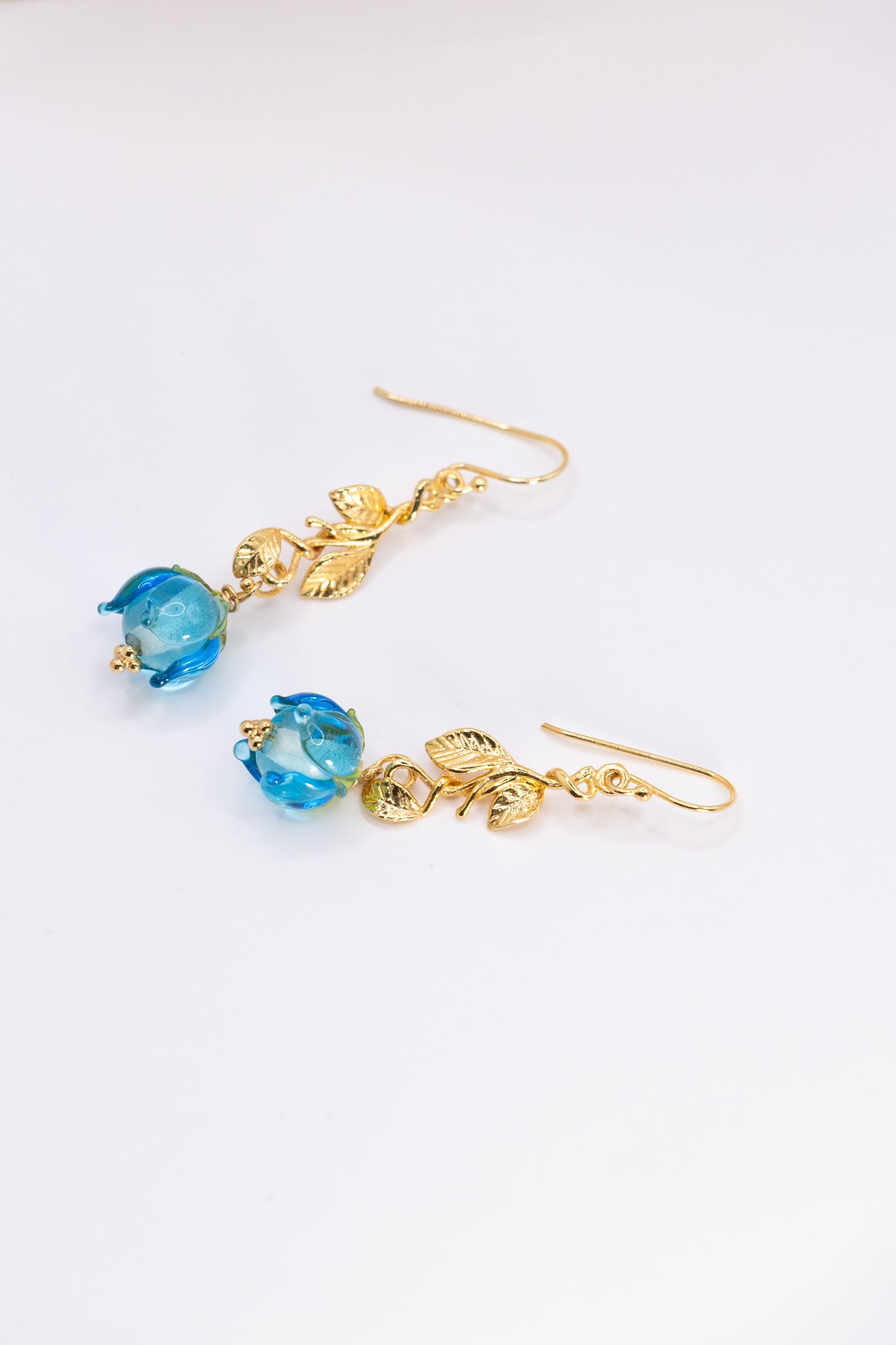 Gold earrings with blue flowers on a white background