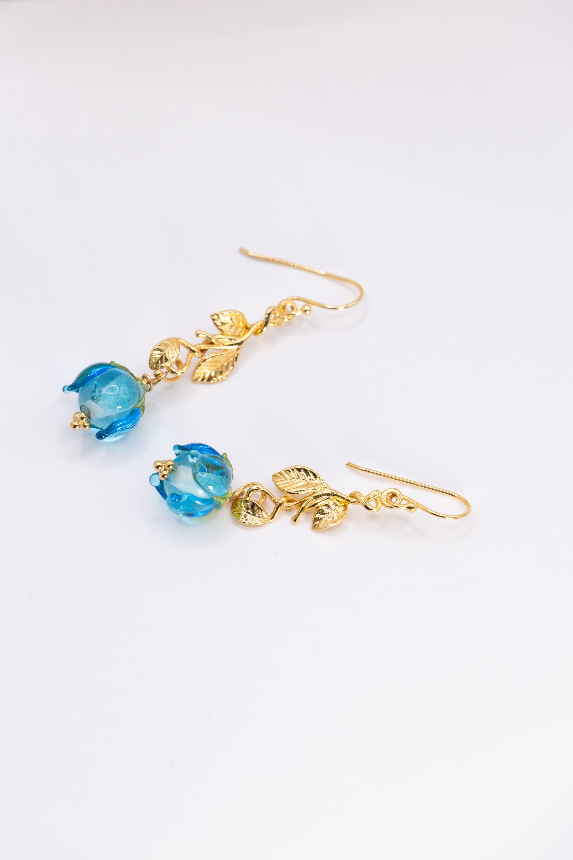 Gold earrings with blue flowers on a white background