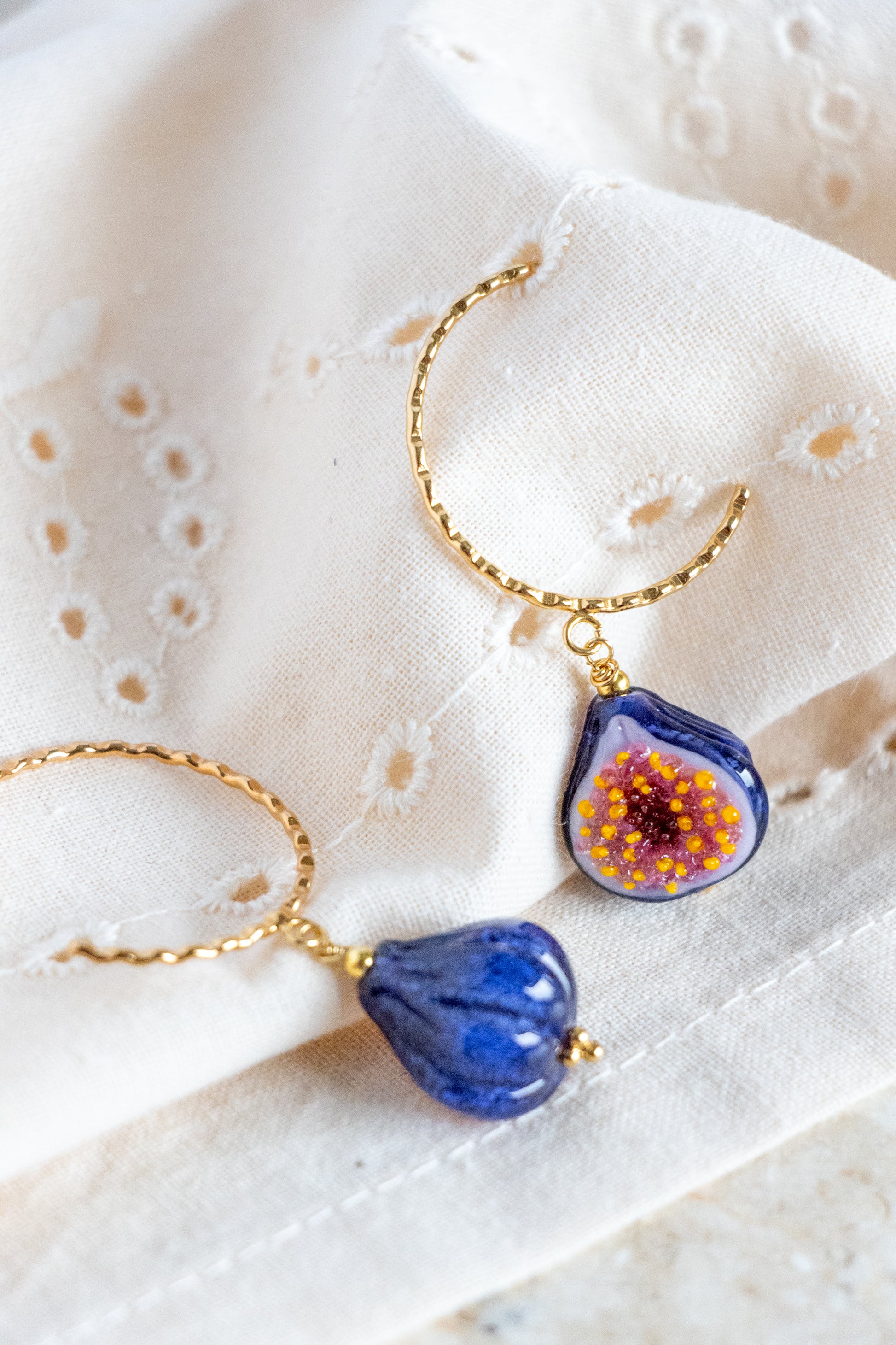 Pair of blue floral earrings with gold accents on a textured white surface