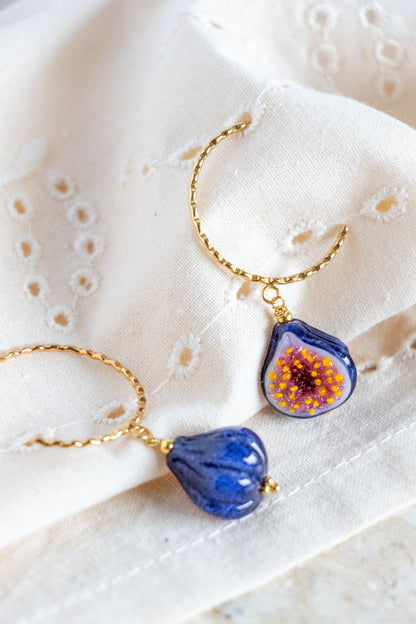 Pair of blue floral earrings with gold accents on a textured white surface