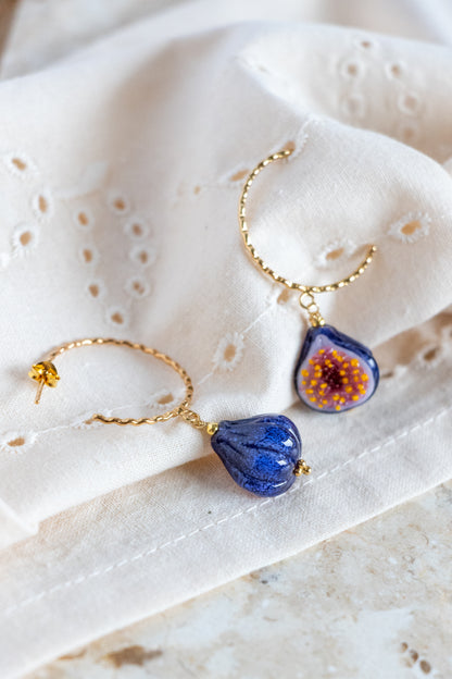 Pair of earrings with blue and gold elements on a textured white surface