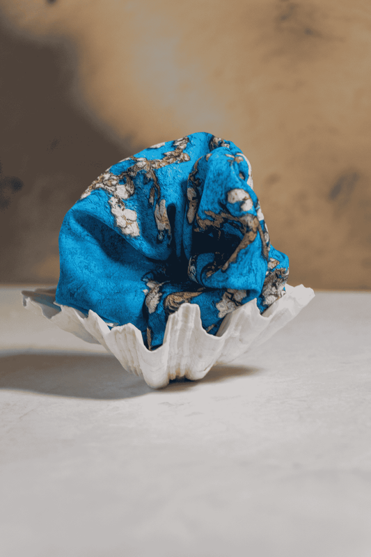 Blue Scrunchie in a sea shell on a neutral background