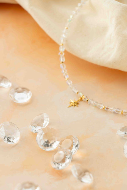 Necklace with clear beads and a star charm on a soft beige background