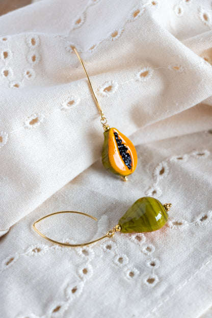Two teardrop-shaped papaya fruit earrings on a white fabric background